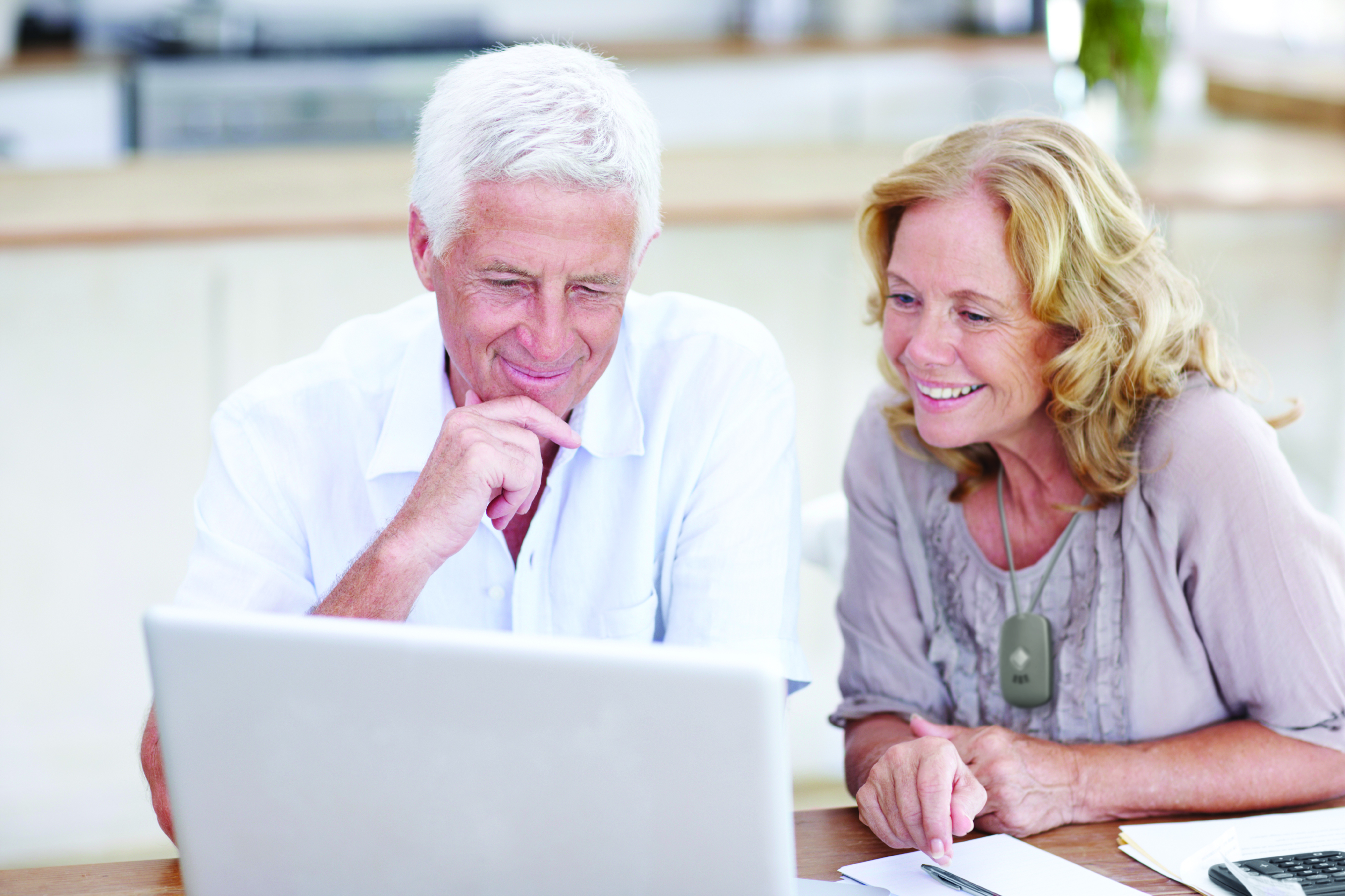 elderly couple with laptop and medical alert system