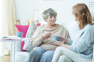 elderly lady speaking with younger woman drinking tea