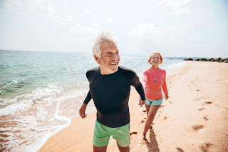 elderly senior man and woman on beach walking