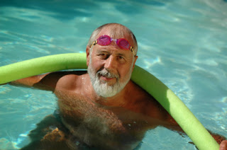 elderly senior man with beard swimming with noodle