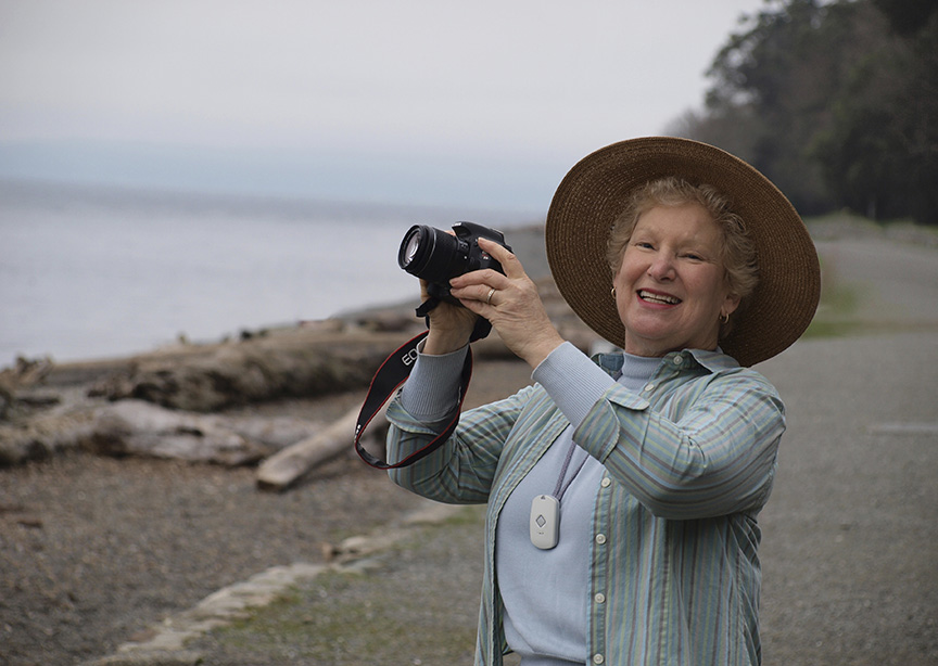 elderly woman on beach with camera and medical alert pendant